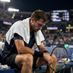 Exhausted tennis player resting on the bench during a night match — tennis recovery tips for players running on empty